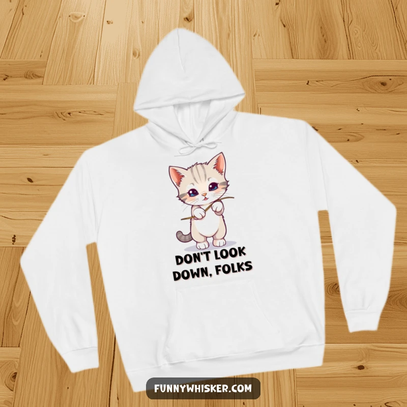 Funny kitten precariously balancing on a shaky whisker, printed on a cozy hoodie, a delightful funny gift.