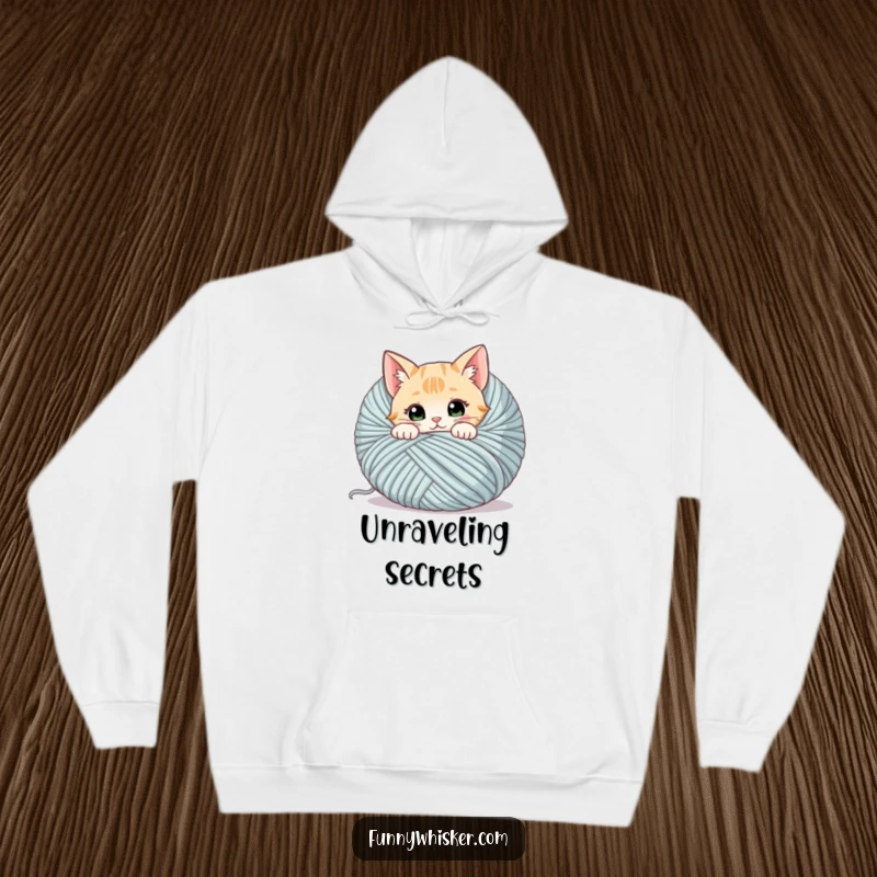 Funny cat hoodie showing a curious cat peeking from behind a large ball of yarn, whiskers twitching, perfect for lounging.