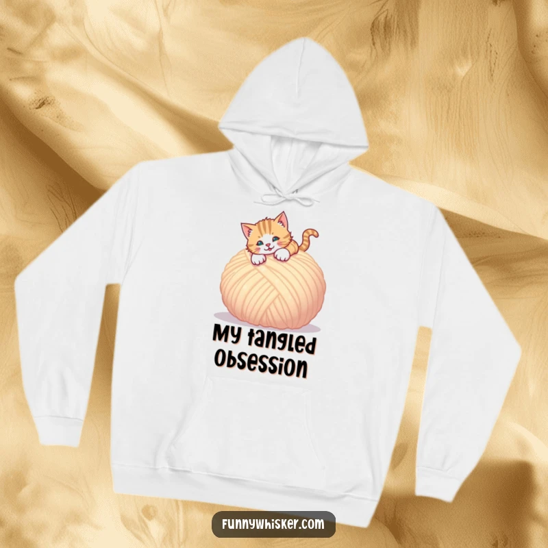 Funny hoodie featuring a cat playfully leaping onto a huge, fluffy ball of yarn, full of energy.